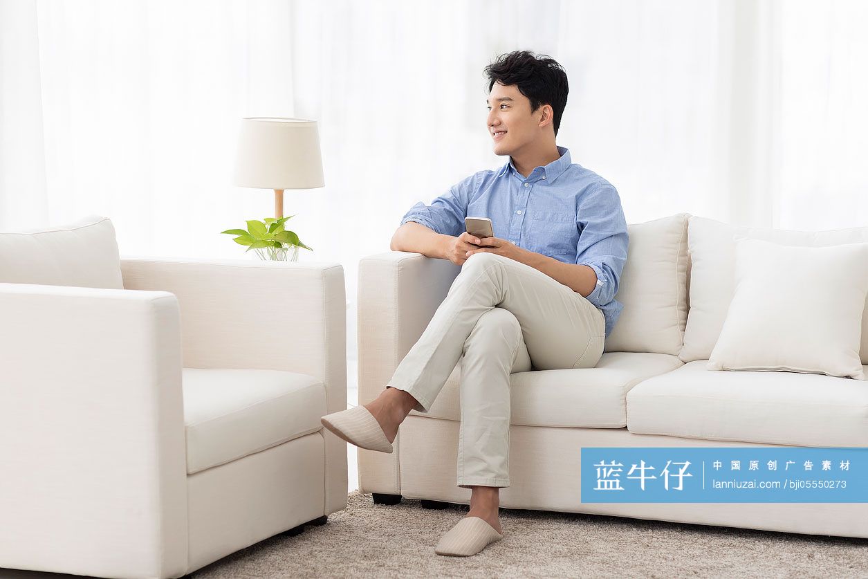 开心的年轻男子坐在沙发上