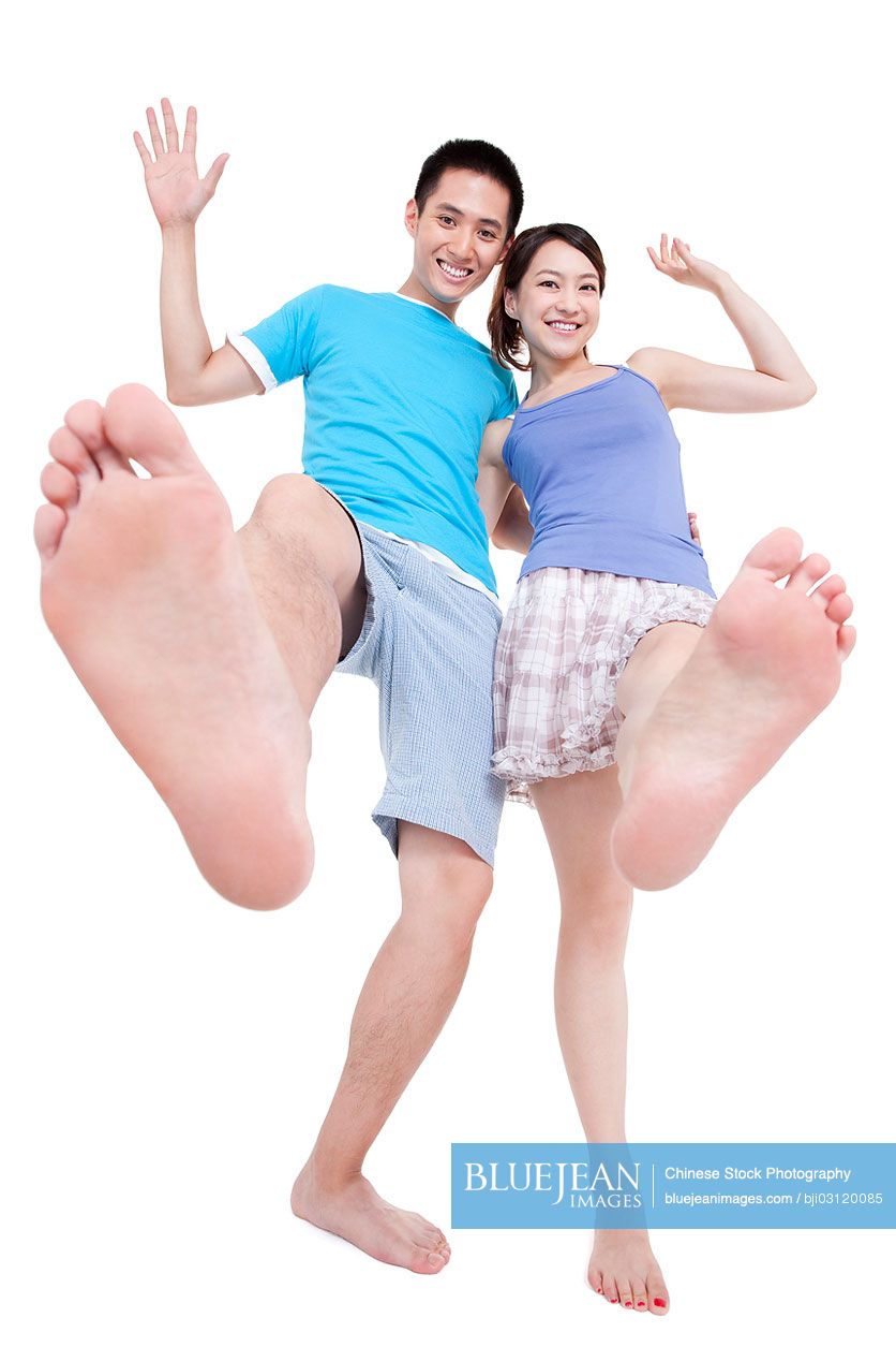 Cheerful young Chinese couple walking with bare feet