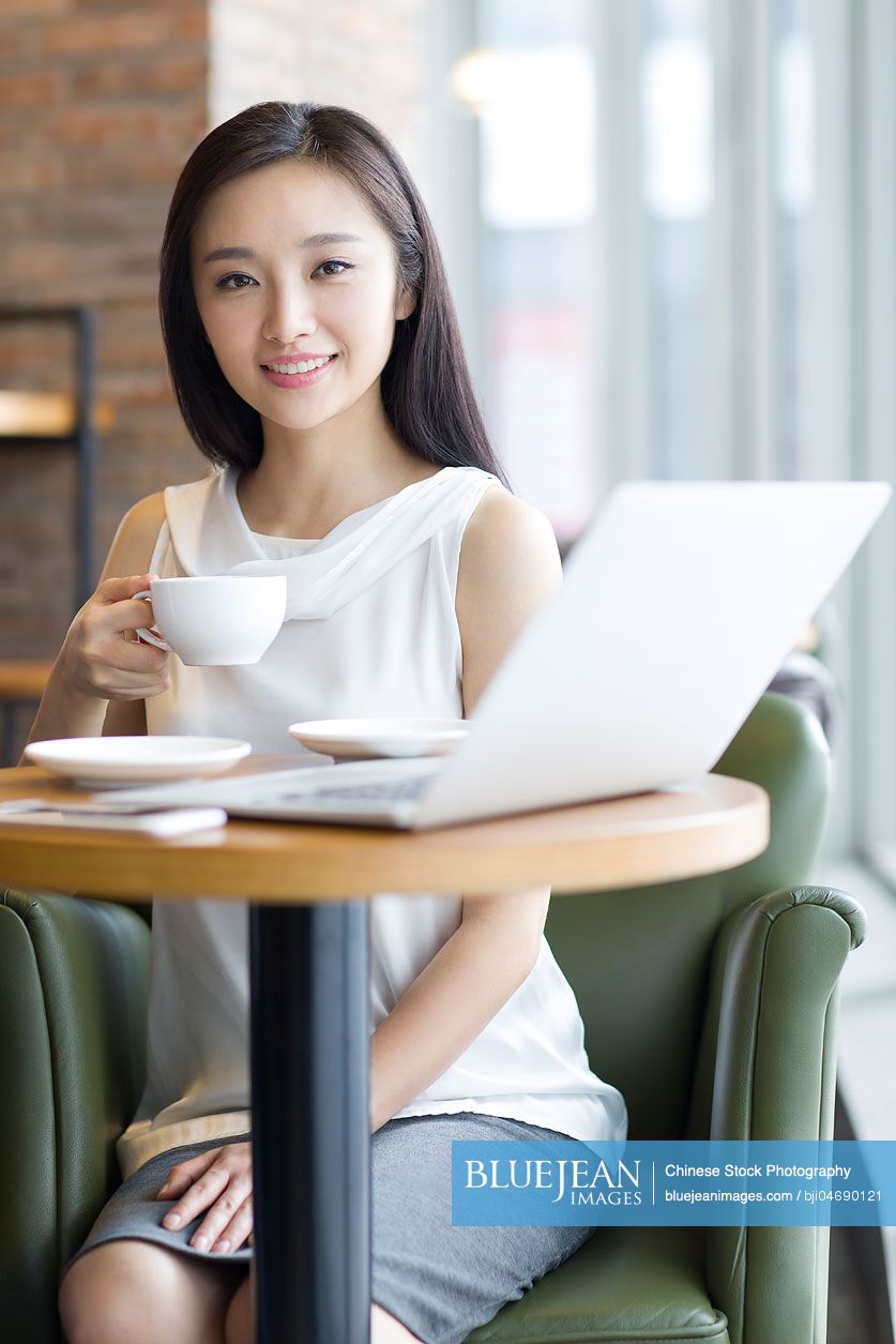 Young Chinese woman working with laptop in café