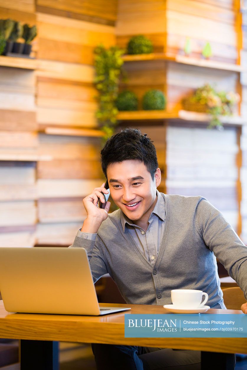 Young Chinese man on the phone in coffee shop