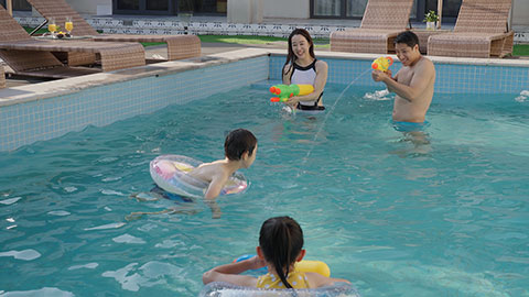 Happy family swimming and playing in the sparkling pool