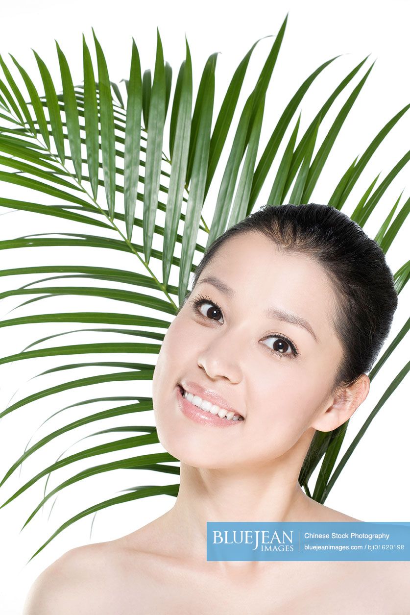 Young Chinese woman in front of tropical leaves