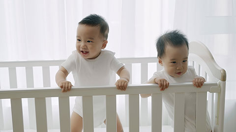 Two twin babies playing in their crib