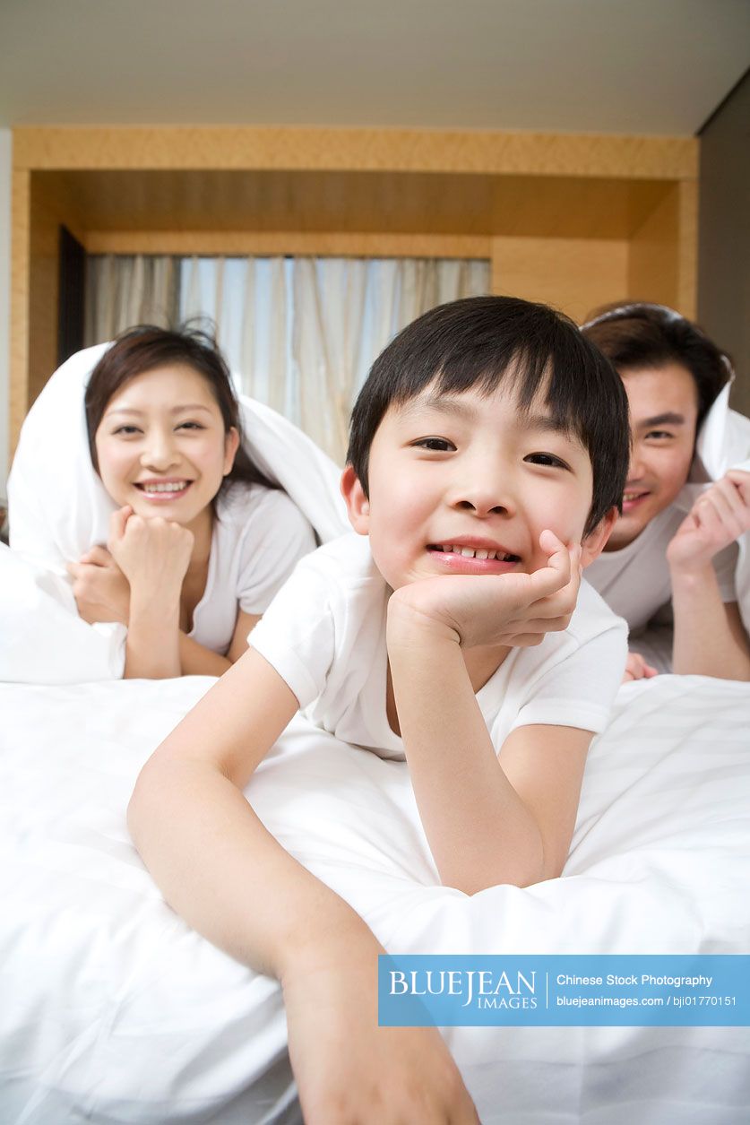 Portrait of a young Chinese family on a bed