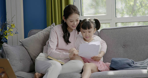 Little girl taking an online class with her mom keeping her company