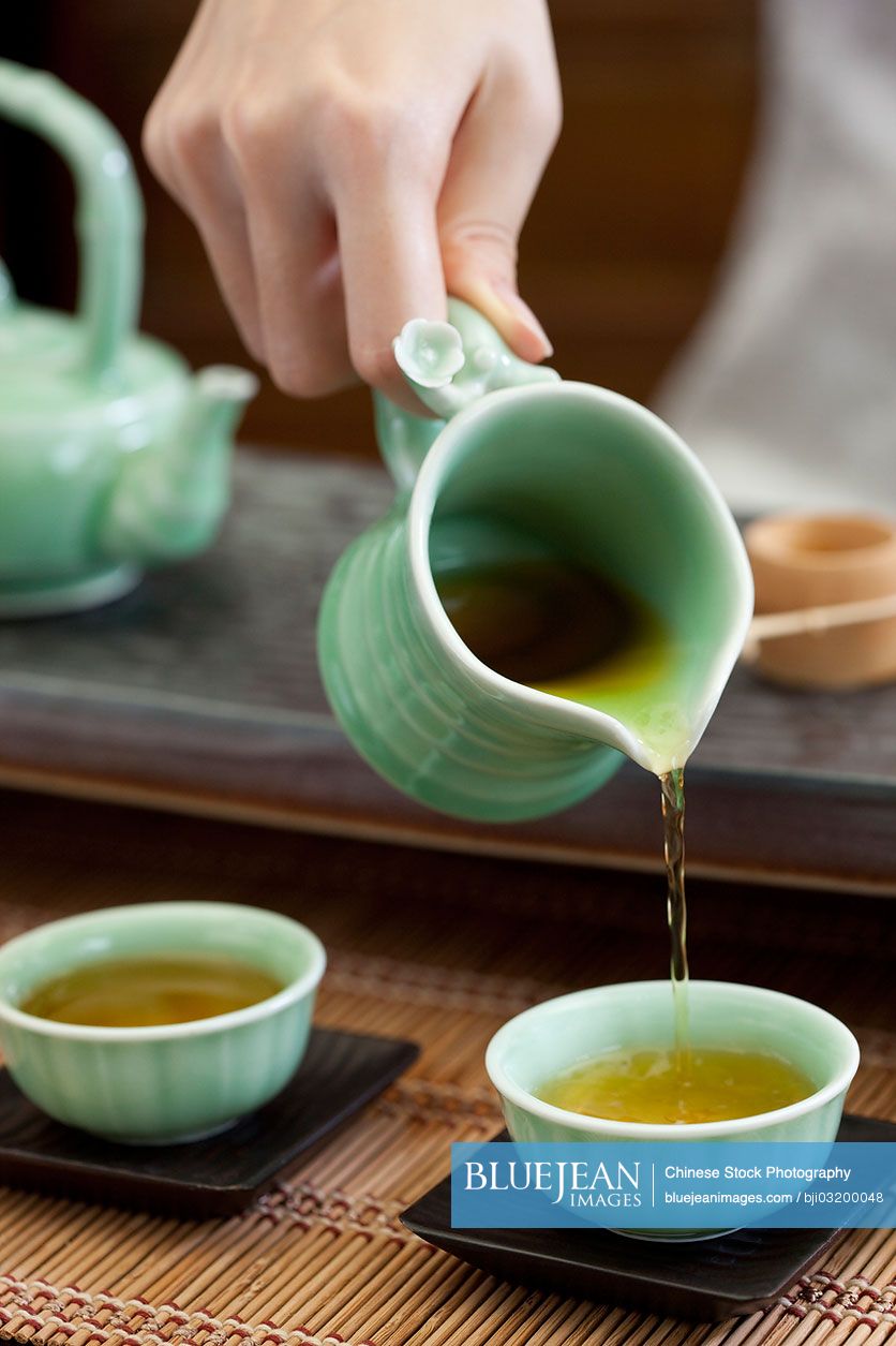 Female Chinese pouring tea into tea cups