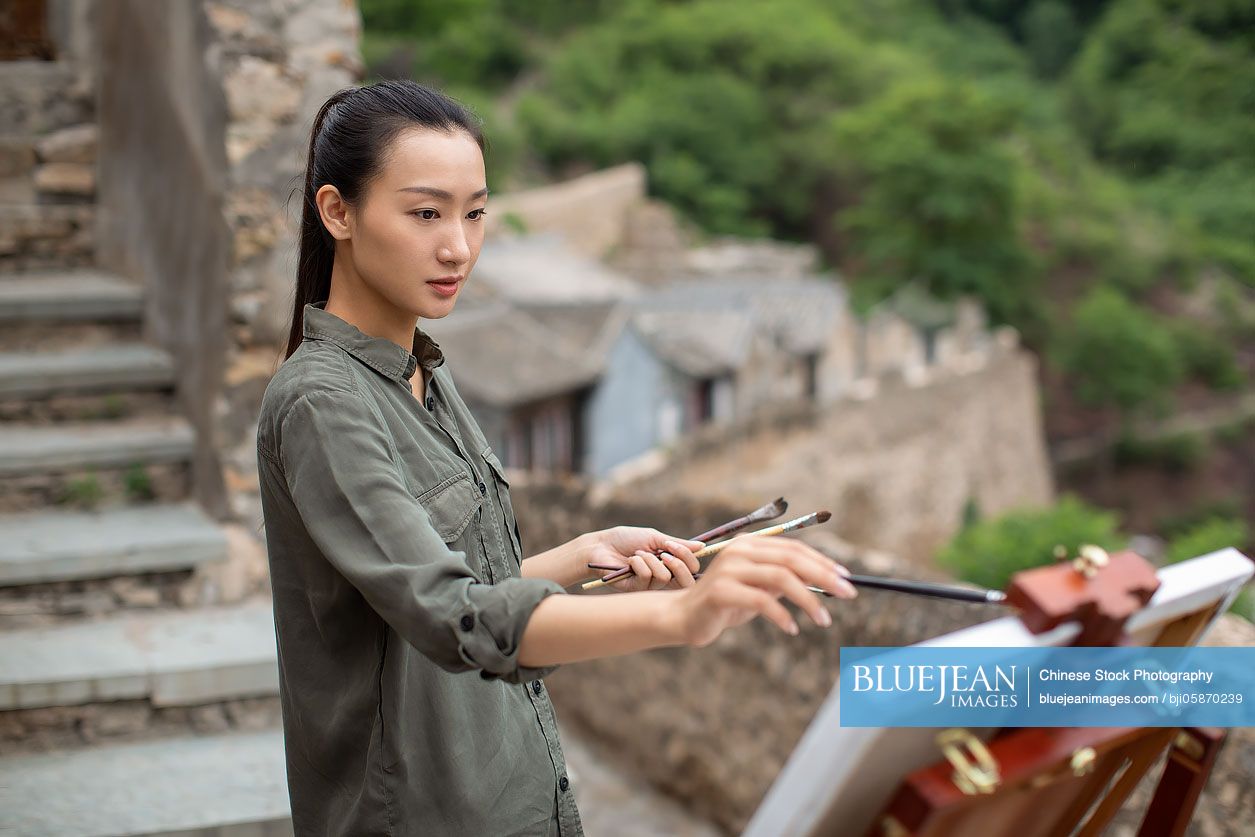 Young Chinese artist painting outdoors