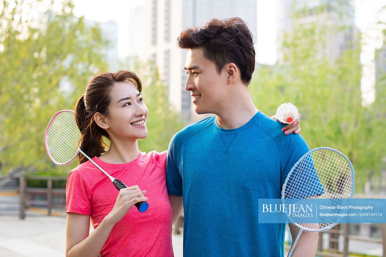 Happy young Chinese couple playing badminton in park