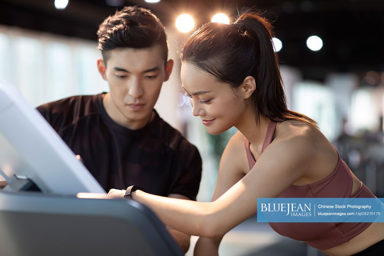 Young Chinese woman working out with personal trainer at gym