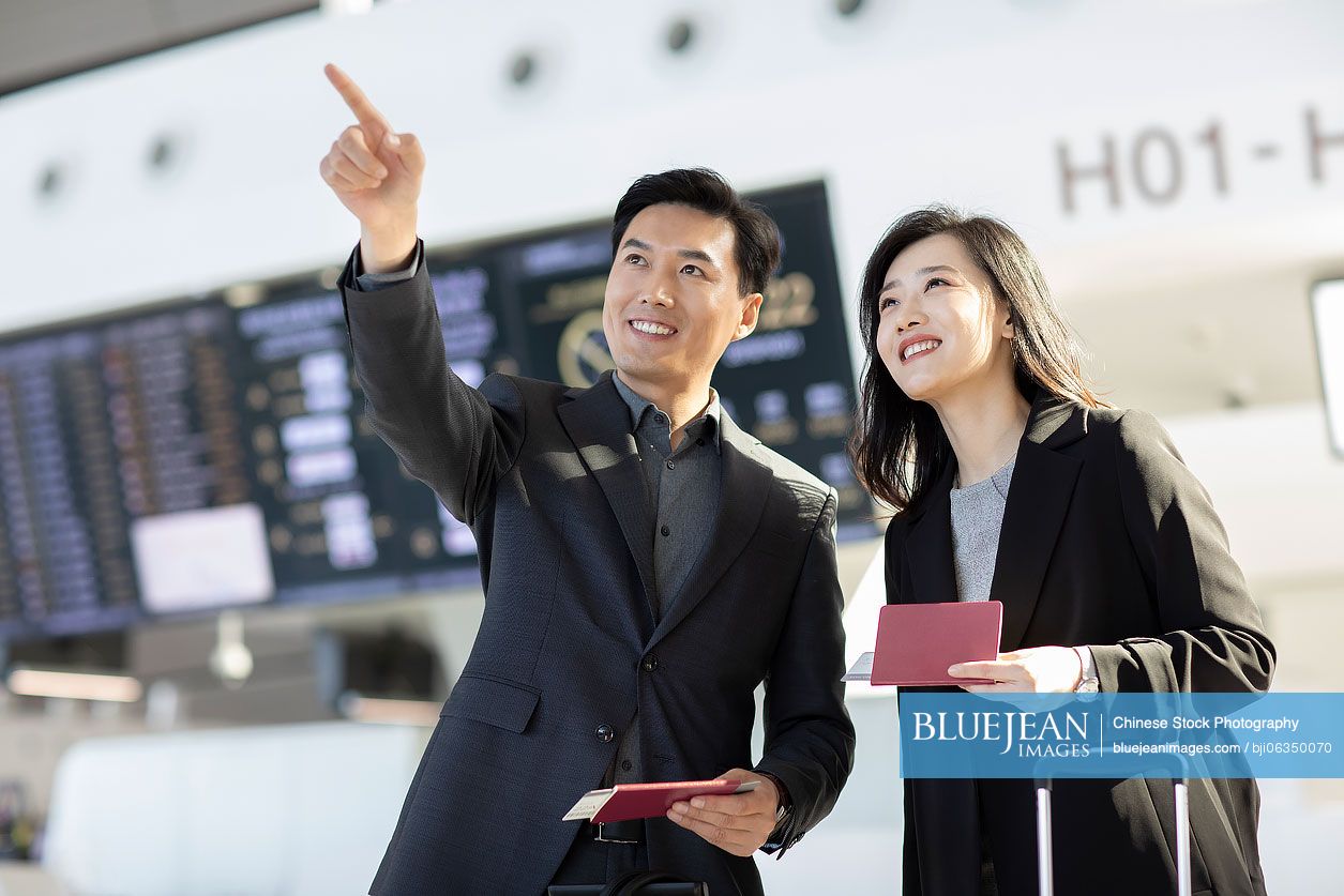 Successful Chinese business people with airplane tickets at airport