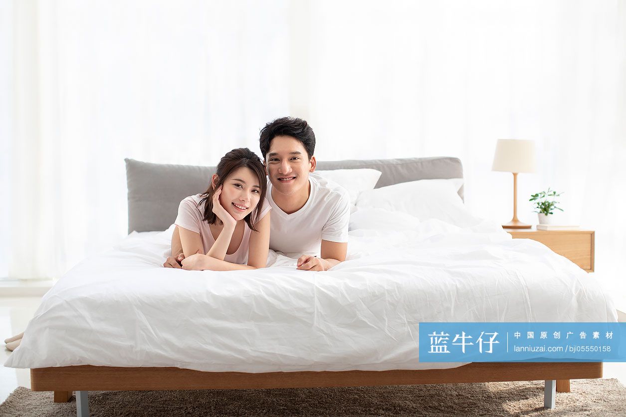 开心的年轻情侣趴在床上