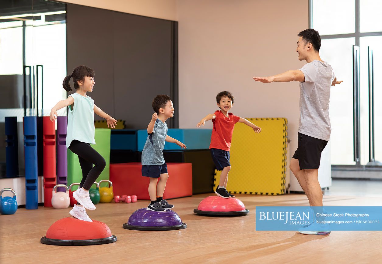 Cute Chinese children having exercise class in gym