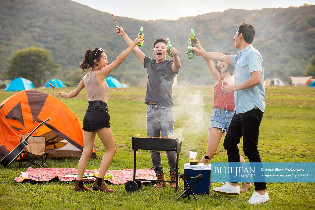 Happy young Chinese friends barbecuing outdoors
