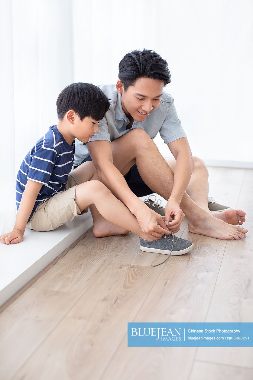 Chinese father teaching his son to tie shoelaces