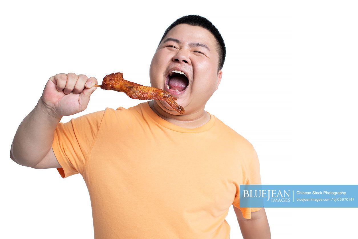 Young Chinese man eating fried food