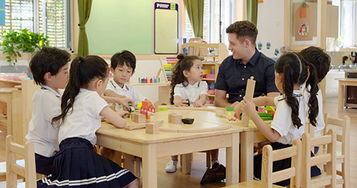 Foreign teacher and children playing train set in classroom,4K