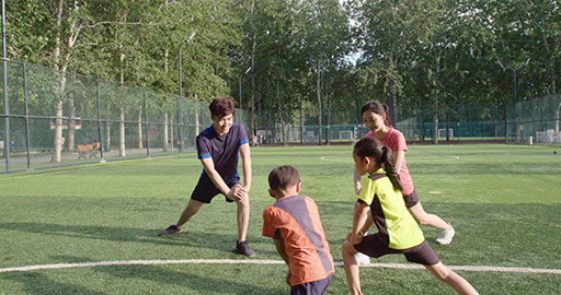 Happy young Chinese family warming up on soccer field,4K