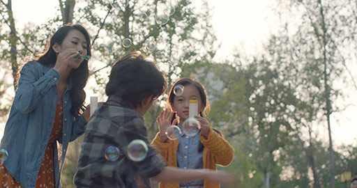 Happy young Chinese family blowing bubbles in park,4K