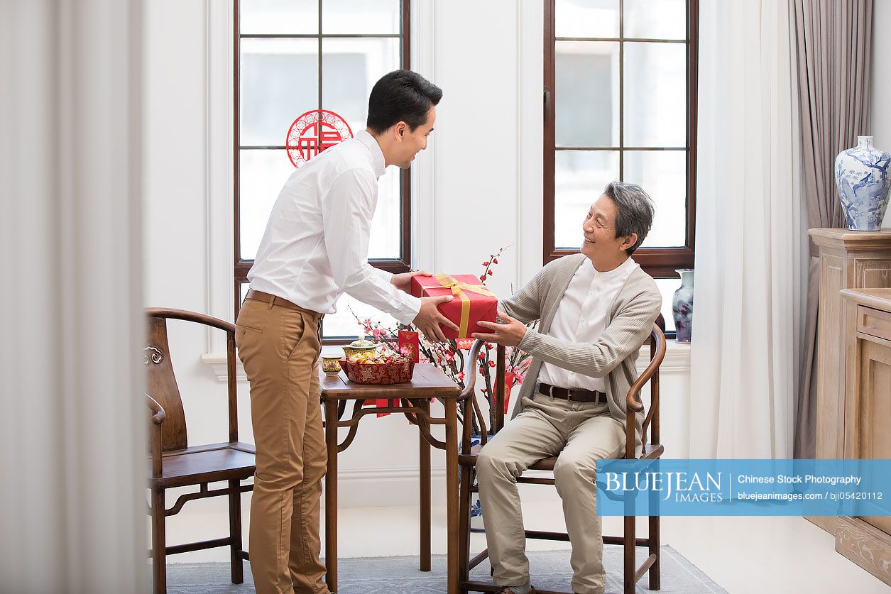 Son giving gift to his father during Chinese New Year