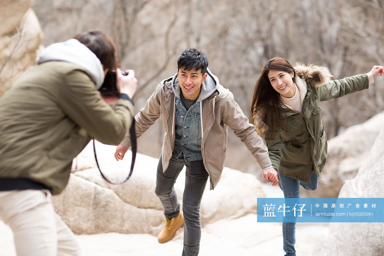 Happy young Chinese friends taking pictures outdoors in winter