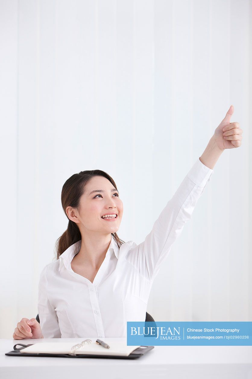 Young Chinese businesswoman doing thumbs up