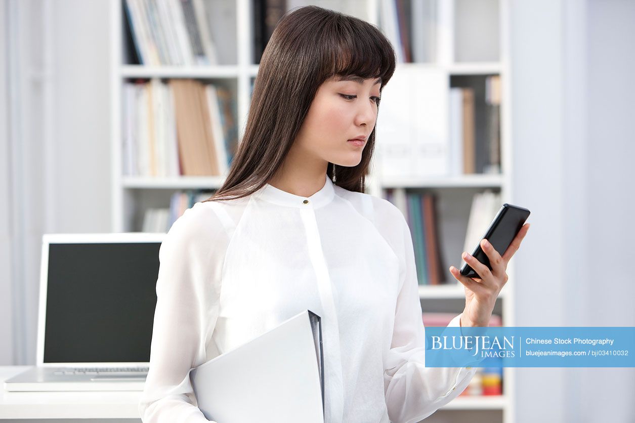 Young Chinese businesswoman with smart phone in the office