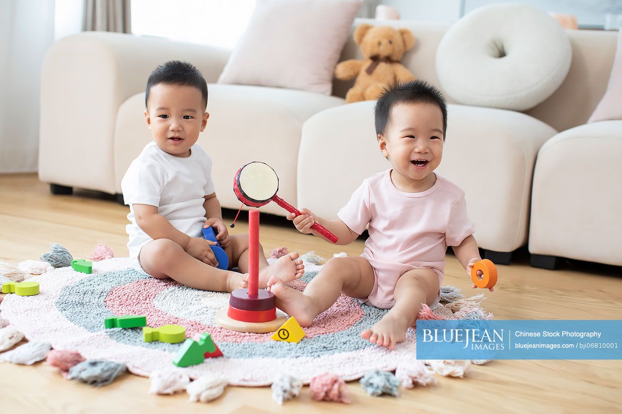 Cute Chinese twin babies playing with toys at home