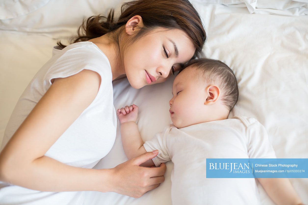 Young Chinese mother and son sleeping in bed