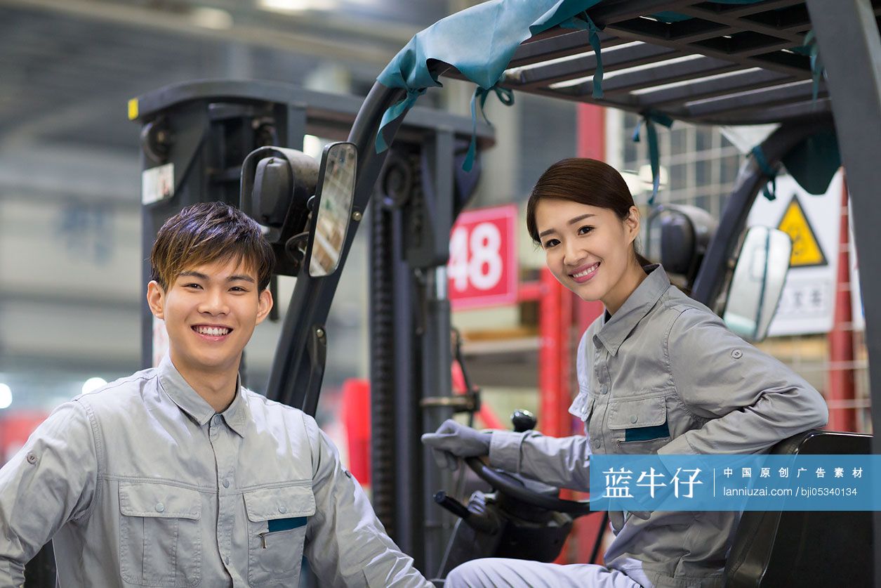 自信的年轻工人在工厂里驾驶叉车