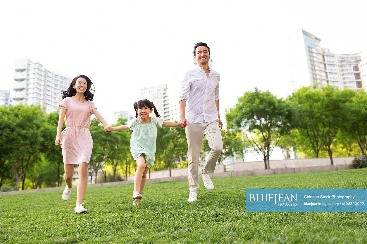 Happy young Chinese family playing in park