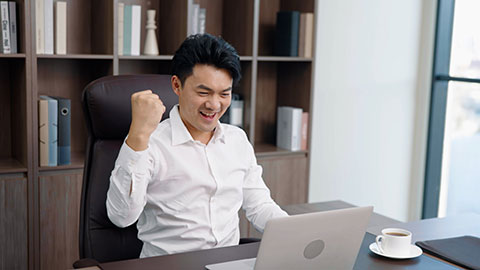 Cheerful Chinese businessman stretching in office