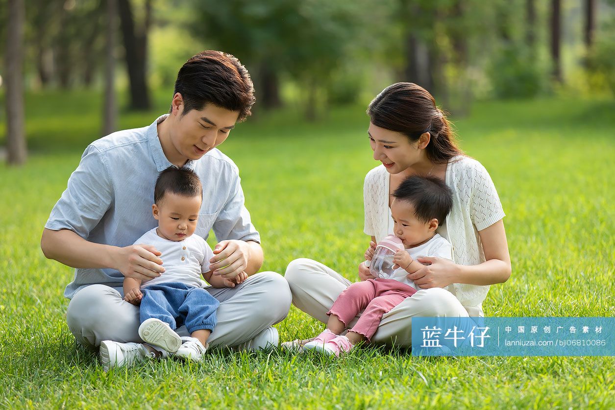 年轻父母在公园陪龙凤胎宝宝玩耍
