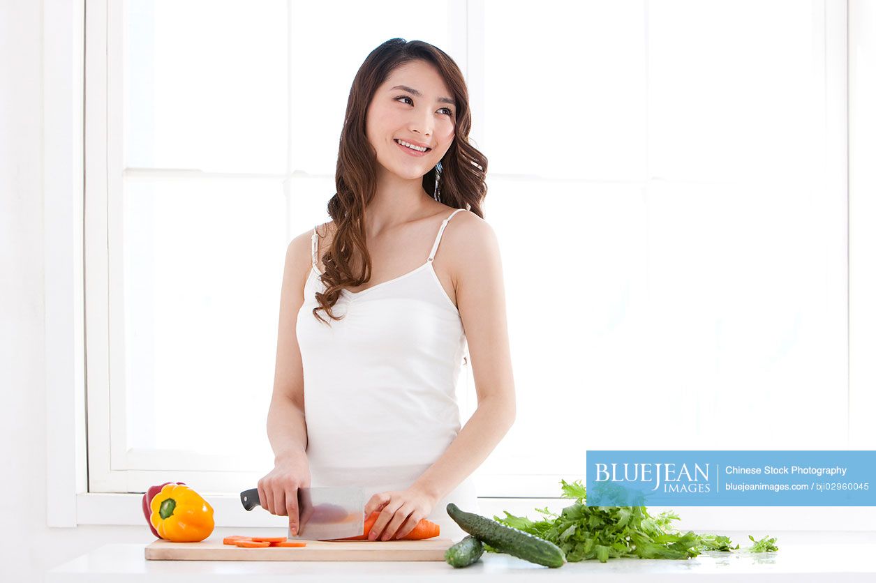 Young Chinese woman cooking in kitchen