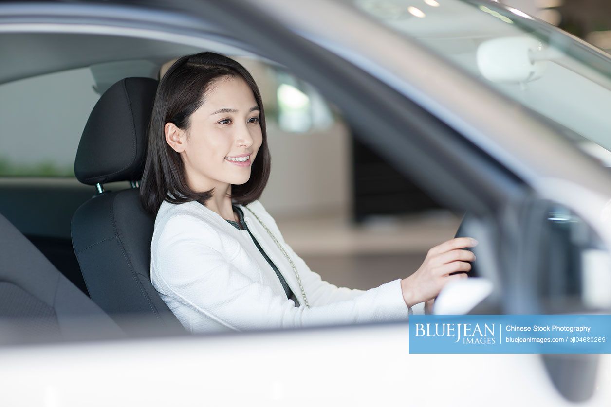 Young chinese woman choosing car in showroom high res stock photo for