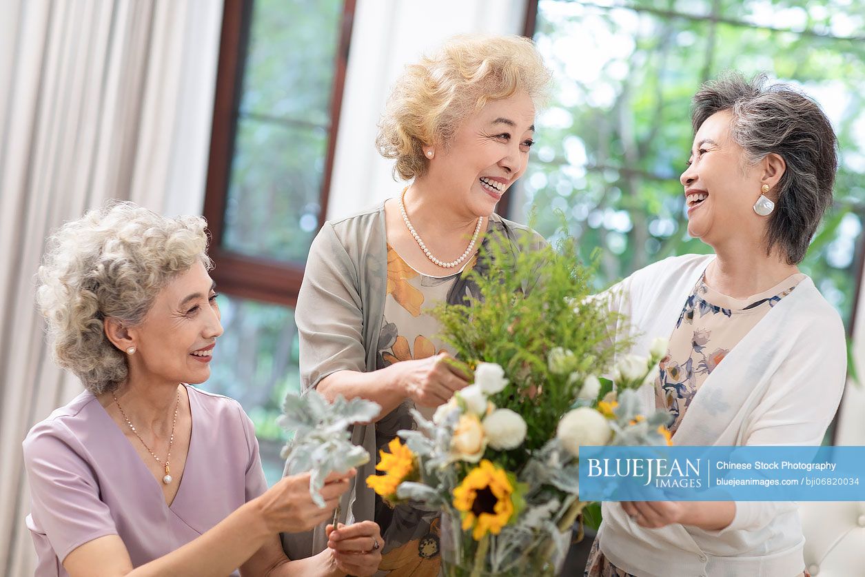 Happy senior Chinese friends arranging flowers together