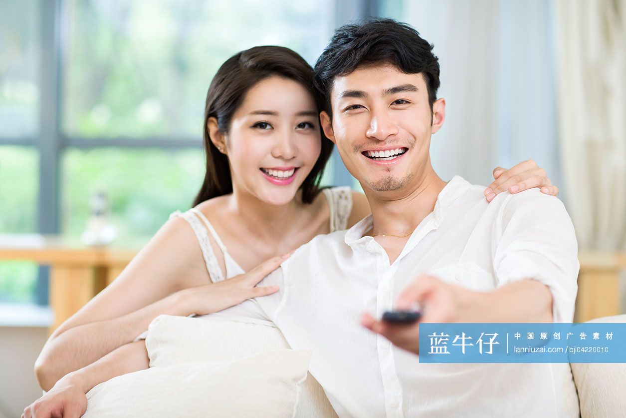 快乐的年轻情侣在家看电视