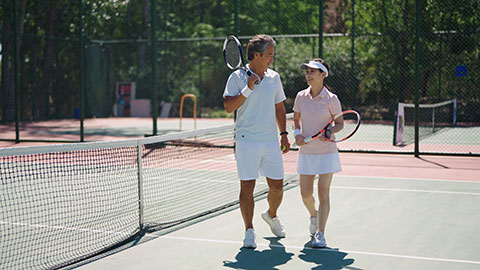 Mature Chinese couple playing tennis ball