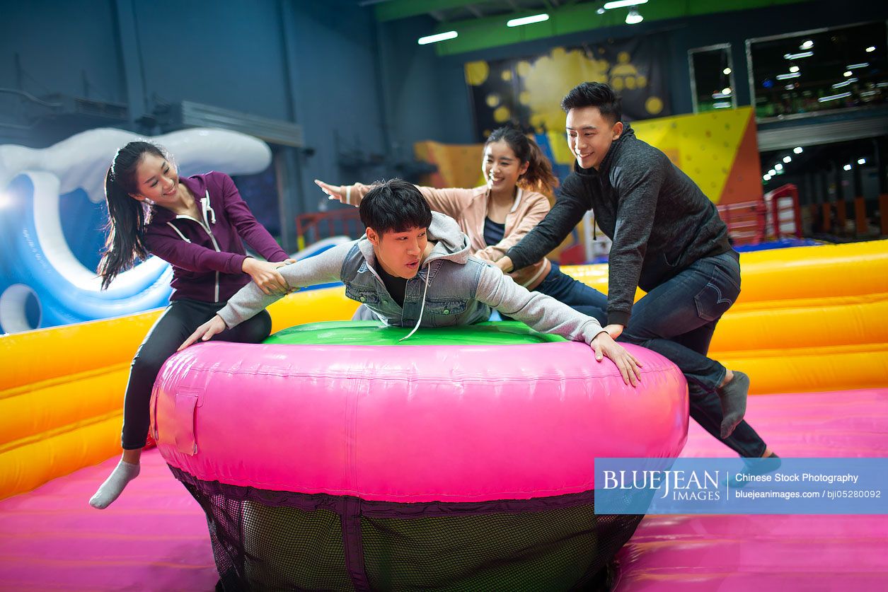 Happy young Chinese friends playing games at amusement park