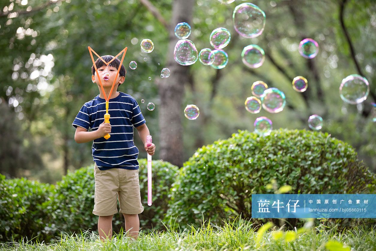 小男孩在草地上吹泡泡