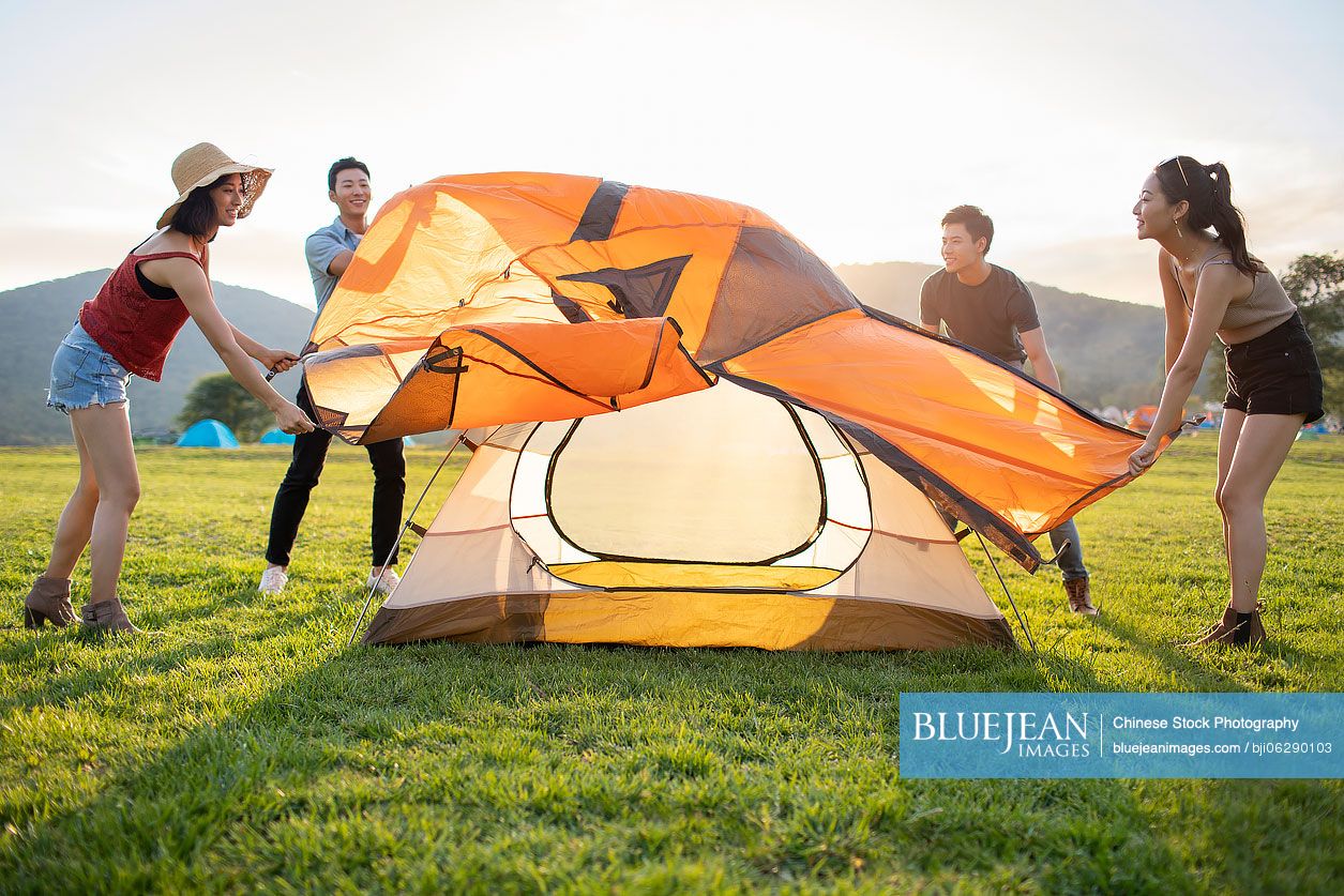 Happy young Chinese friends camping outdoors