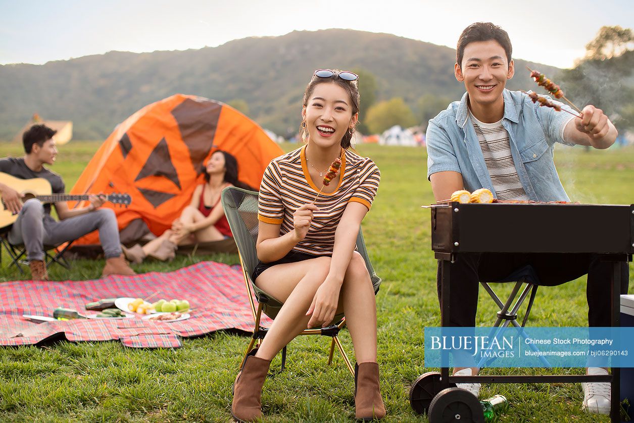 Happy young Chinese friends barbecuing outdoors