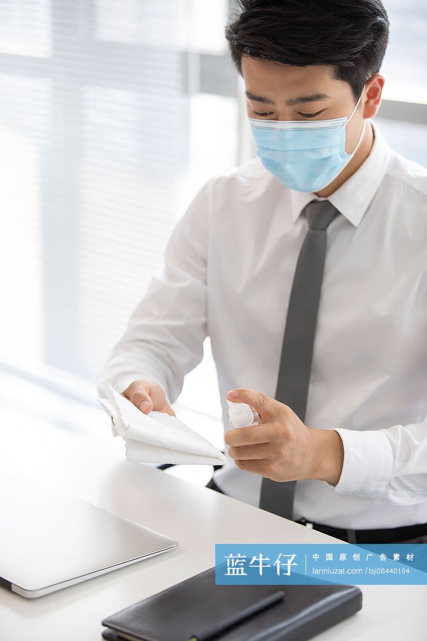 年轻的商务男士在办公室使用消毒液杀菌消毒