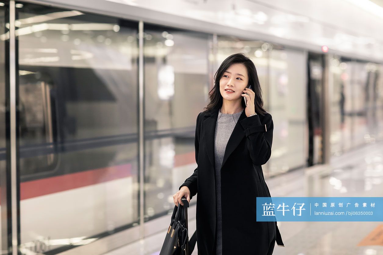 年轻商务女士在地铁站使用手机