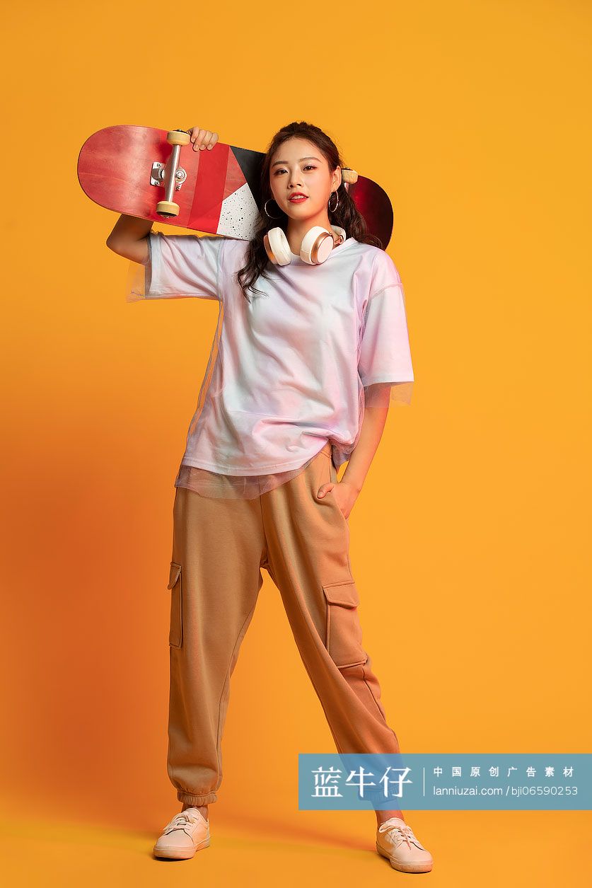 时尚的年轻女孩拿着滑板