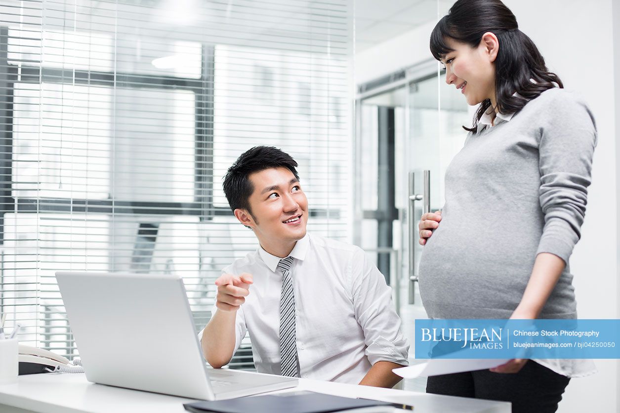 Pregnant Chinese businesswoman working with colleague
