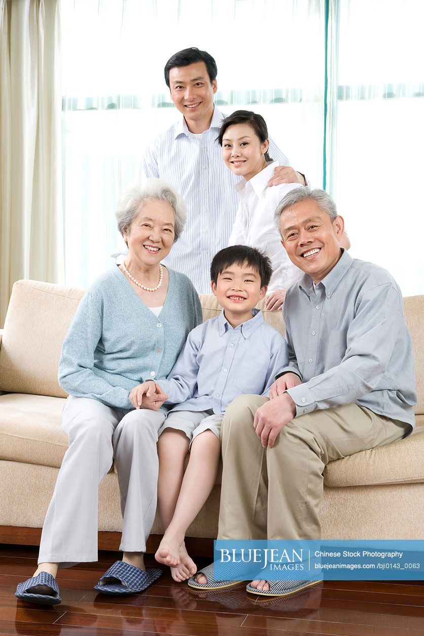 Chinese grandparents and parents pose with son in sofa