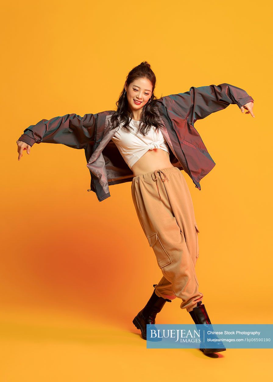 Studio shot of fashionable young Chinese woman dancing