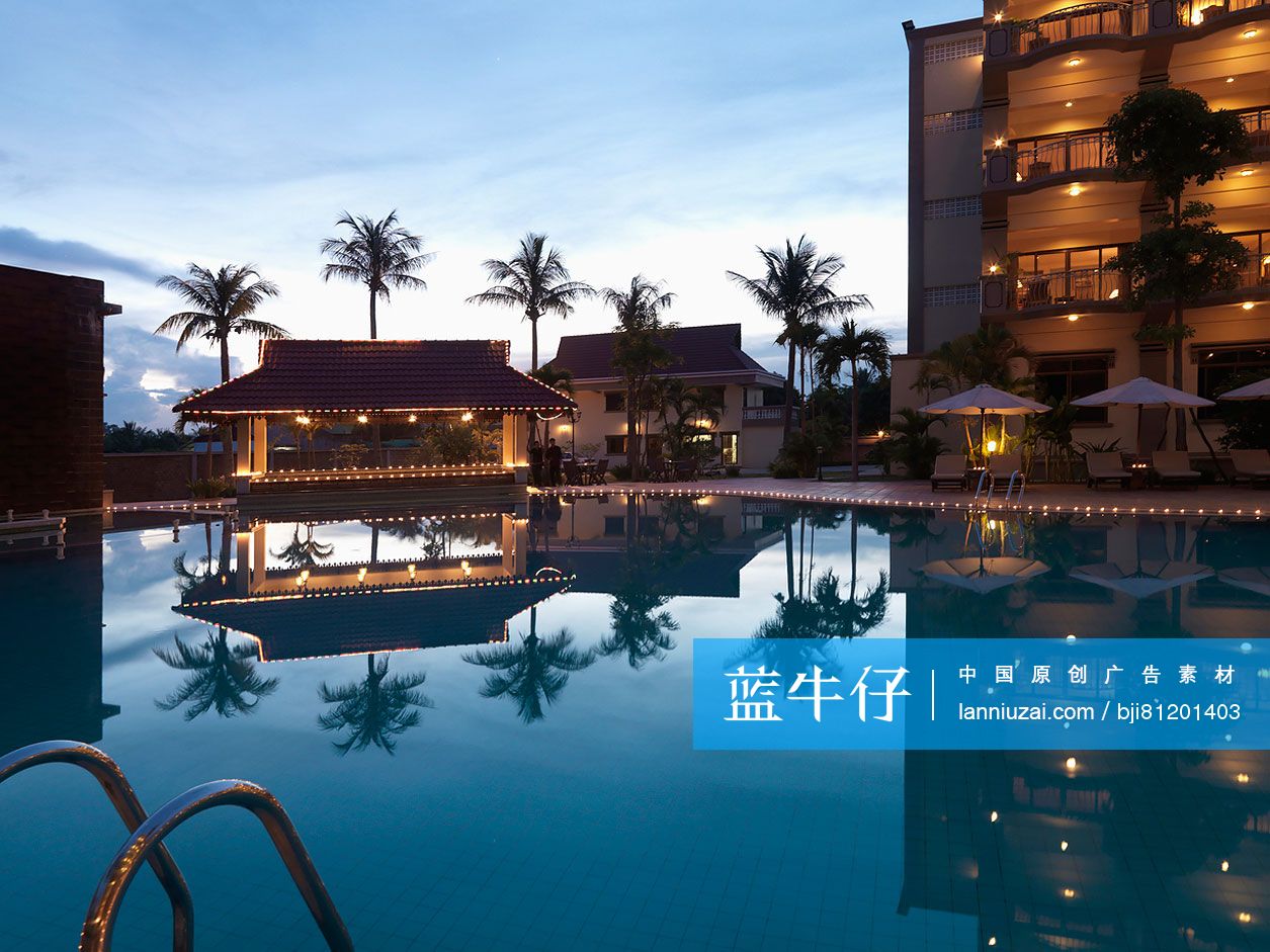 Illuminated hotel building with swimming pool at dusk