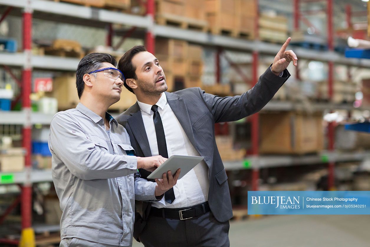 Businessman and engineer talking in the factory