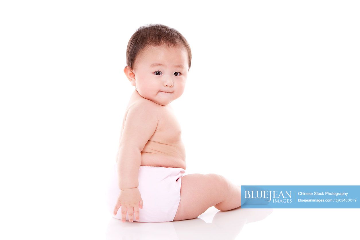 Studio shot of cute Chinese baby sitting on floor